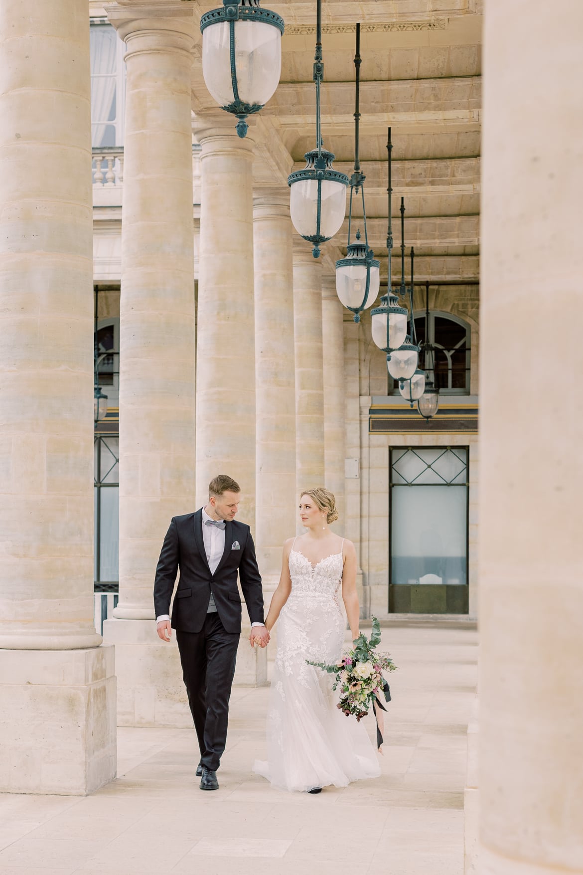 Hochzeitspaar spaziert durch einen Säulengang