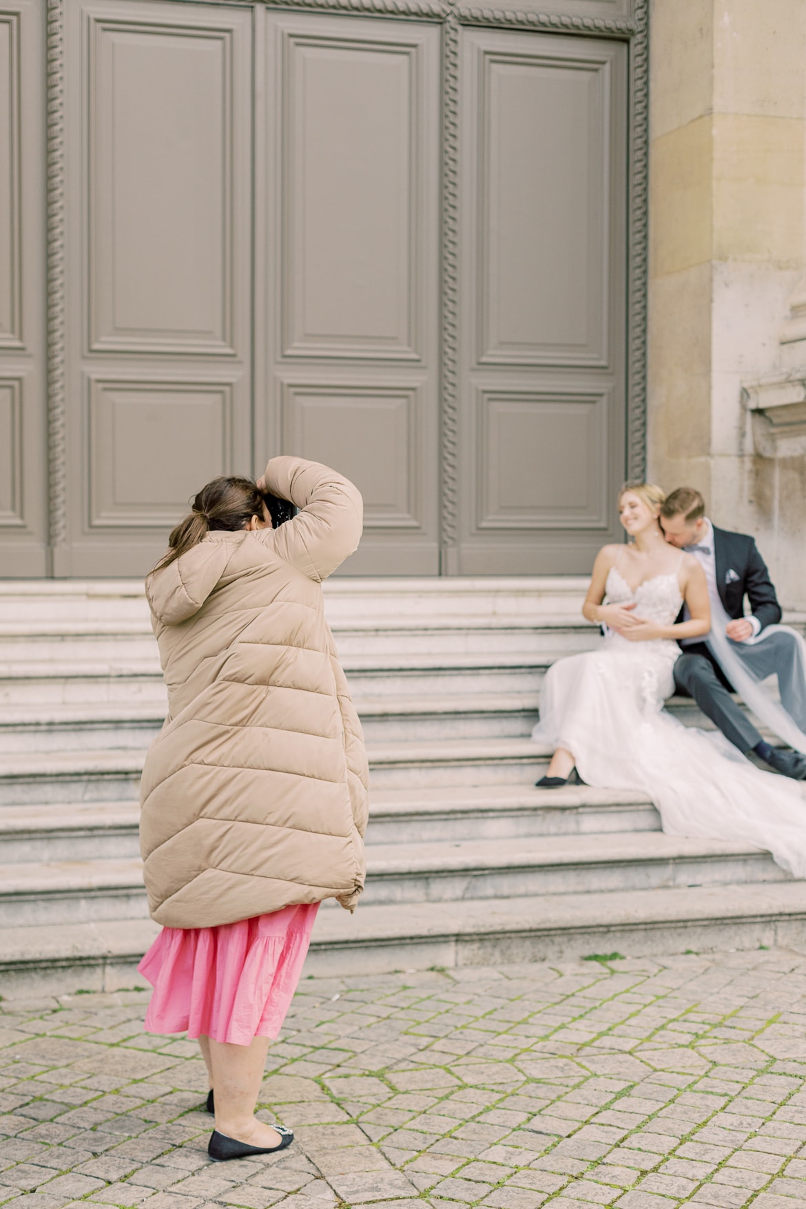 Fotografin fotografiert ein Hochzeitspaar, welches auf einer Treppe sitzt