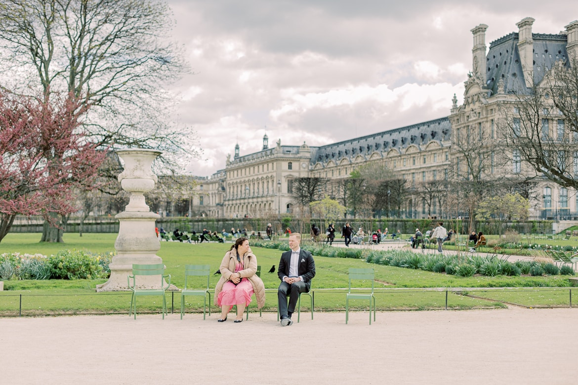 Fotografin und Bräutigam sitzen auf Stühlen im Park