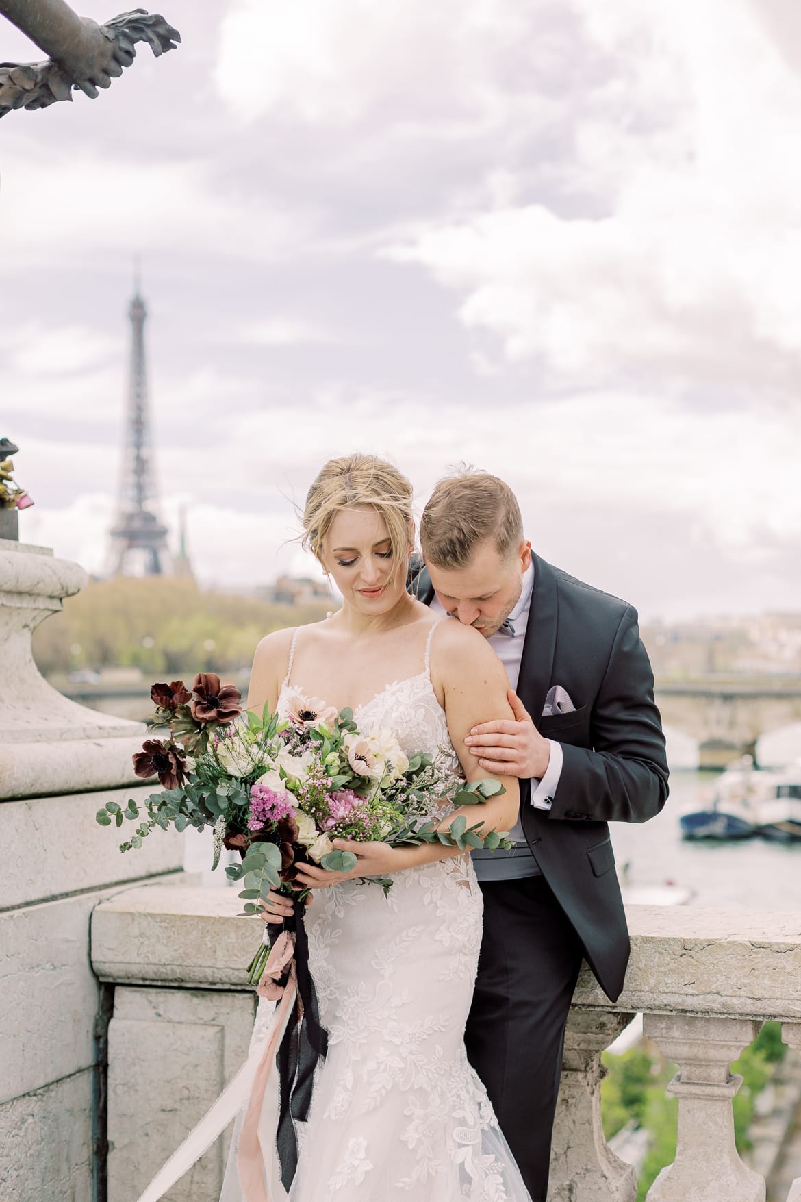 Bräutigam küsst seine Braut auf die Schulter; im Hintergrund sieht man den Eiffelturm
