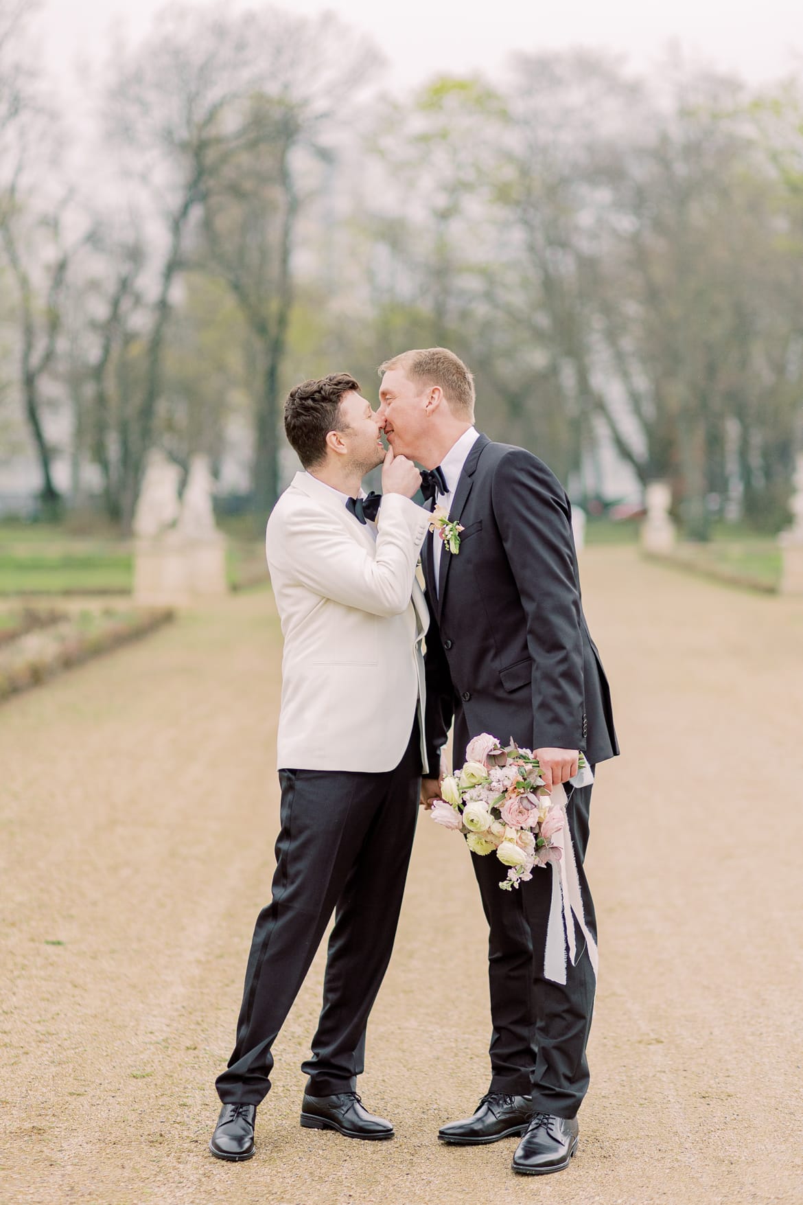 Zwei Männer in Anzügen küssen sich im Park