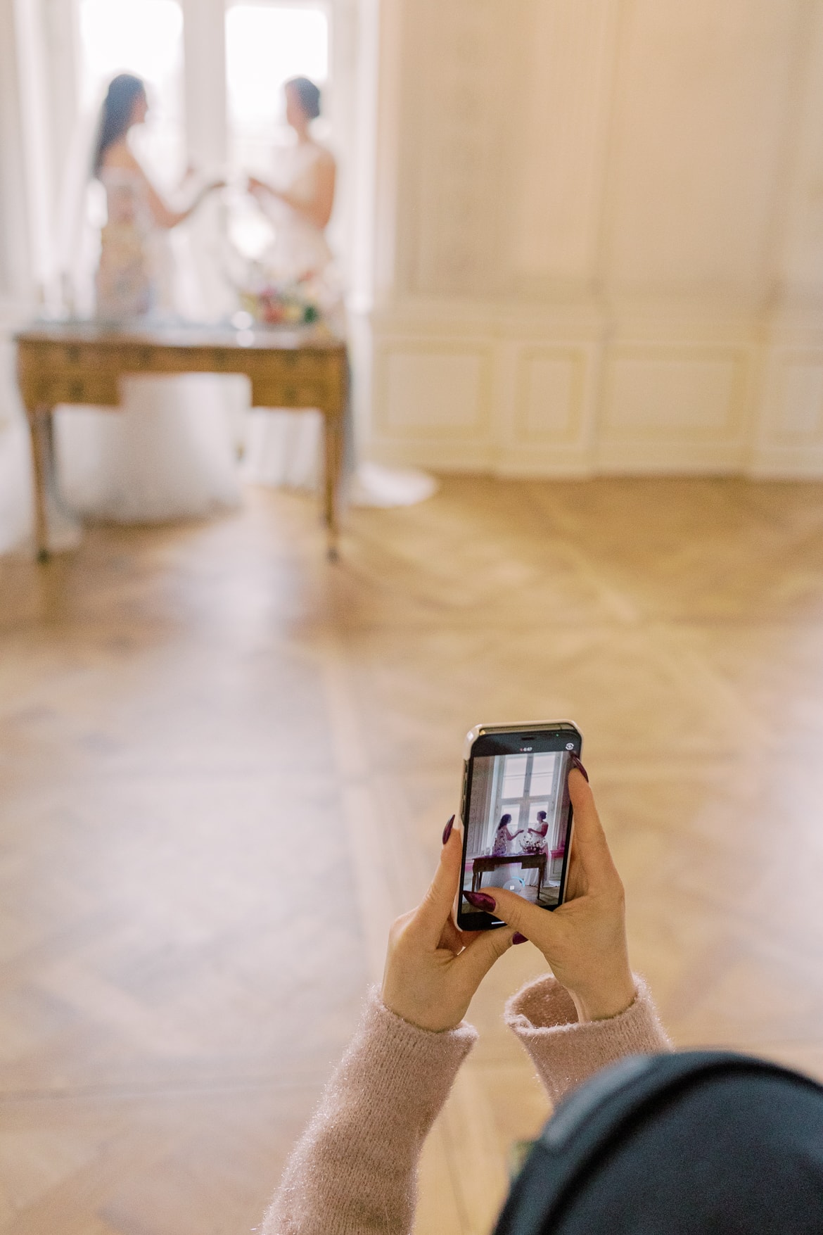 Frau macht mit ihrem Handy ein Foto von zwei Bräuten an der Hochzeitstorte