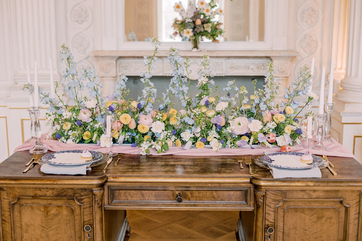 Aufwändiges Table Setting mit vielen Blumen auf einem alten Schreibtisch in einem Ballsaal