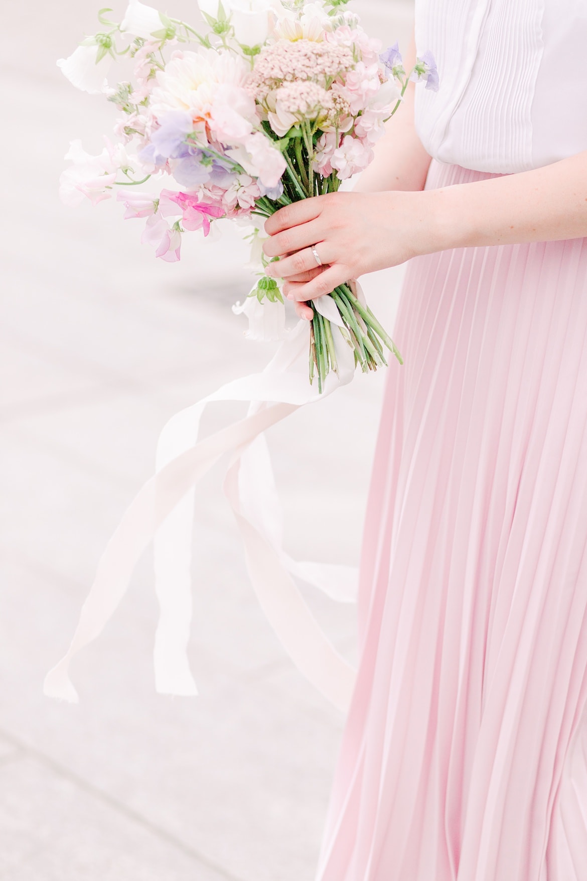 Eine Frau hält einen Blumenstrauß. Sie trägt einen rosa Rock.